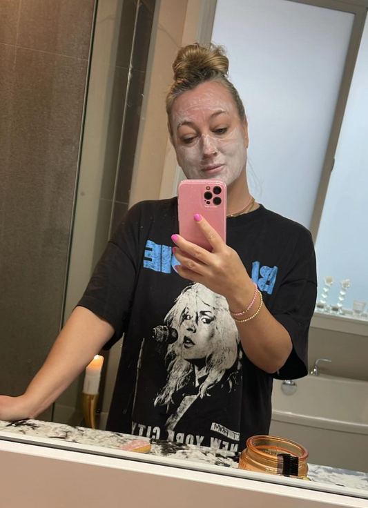 woman in mirror with a face mask on for self care 