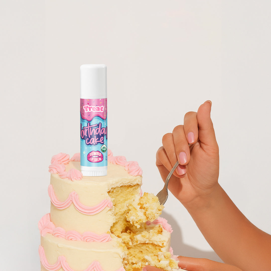 Lip balm labeled 'Birthday Cake' on a cake with a hand holding a fork.