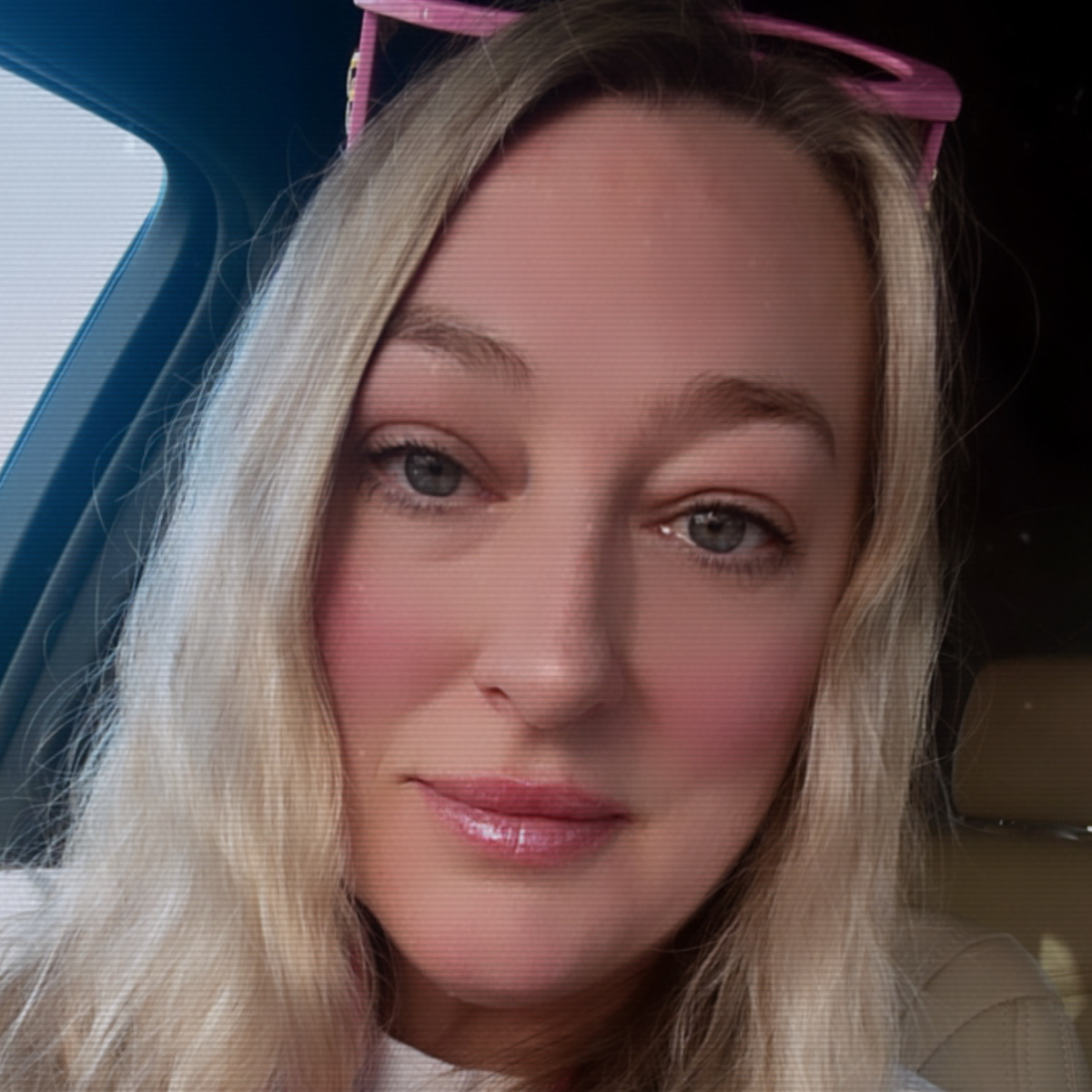 Woman with pink sunglasses on head inside a vehicle