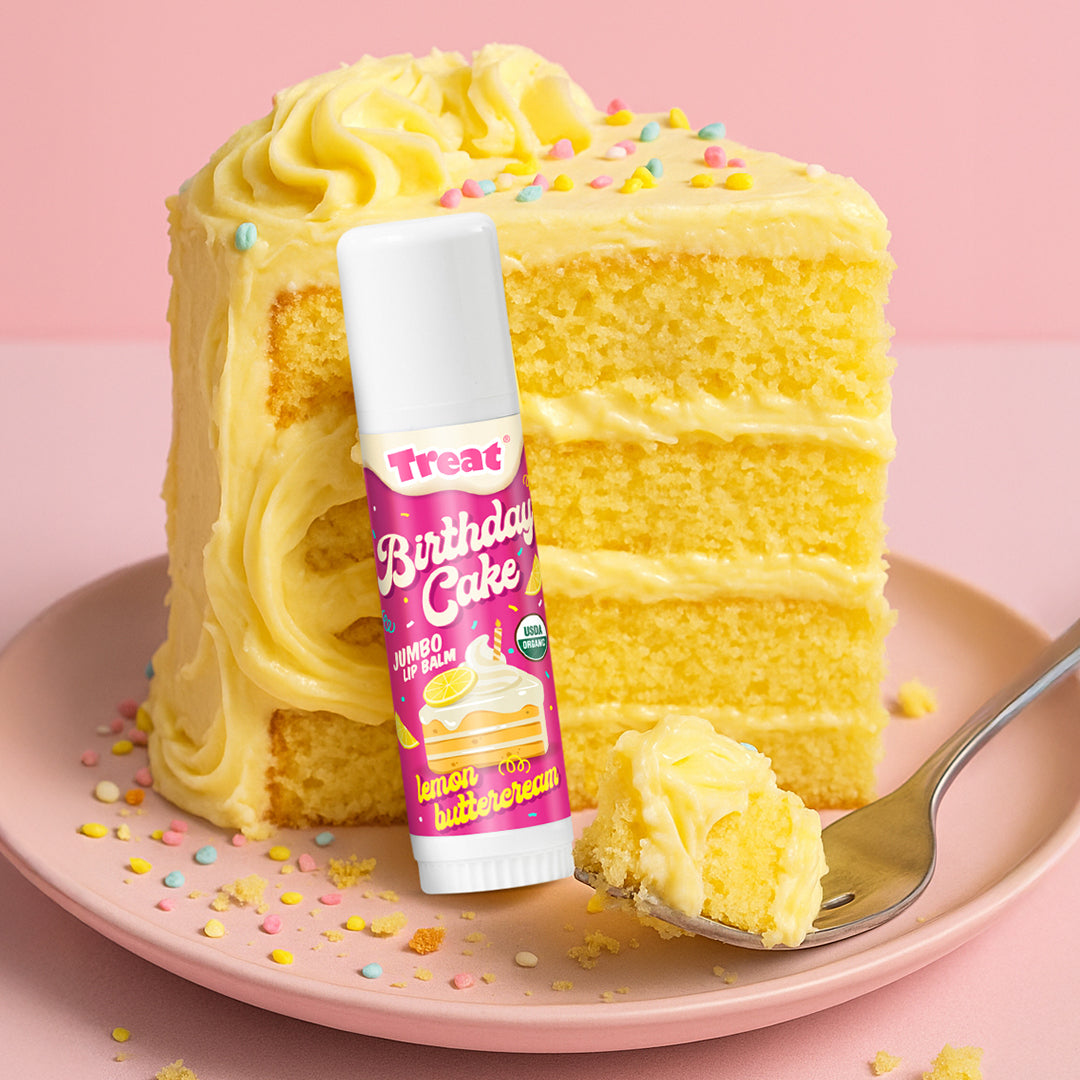 Lip balm labeled 'Birthday Cake' on a slice of yellow cake with colorful sprinkles on a pink background